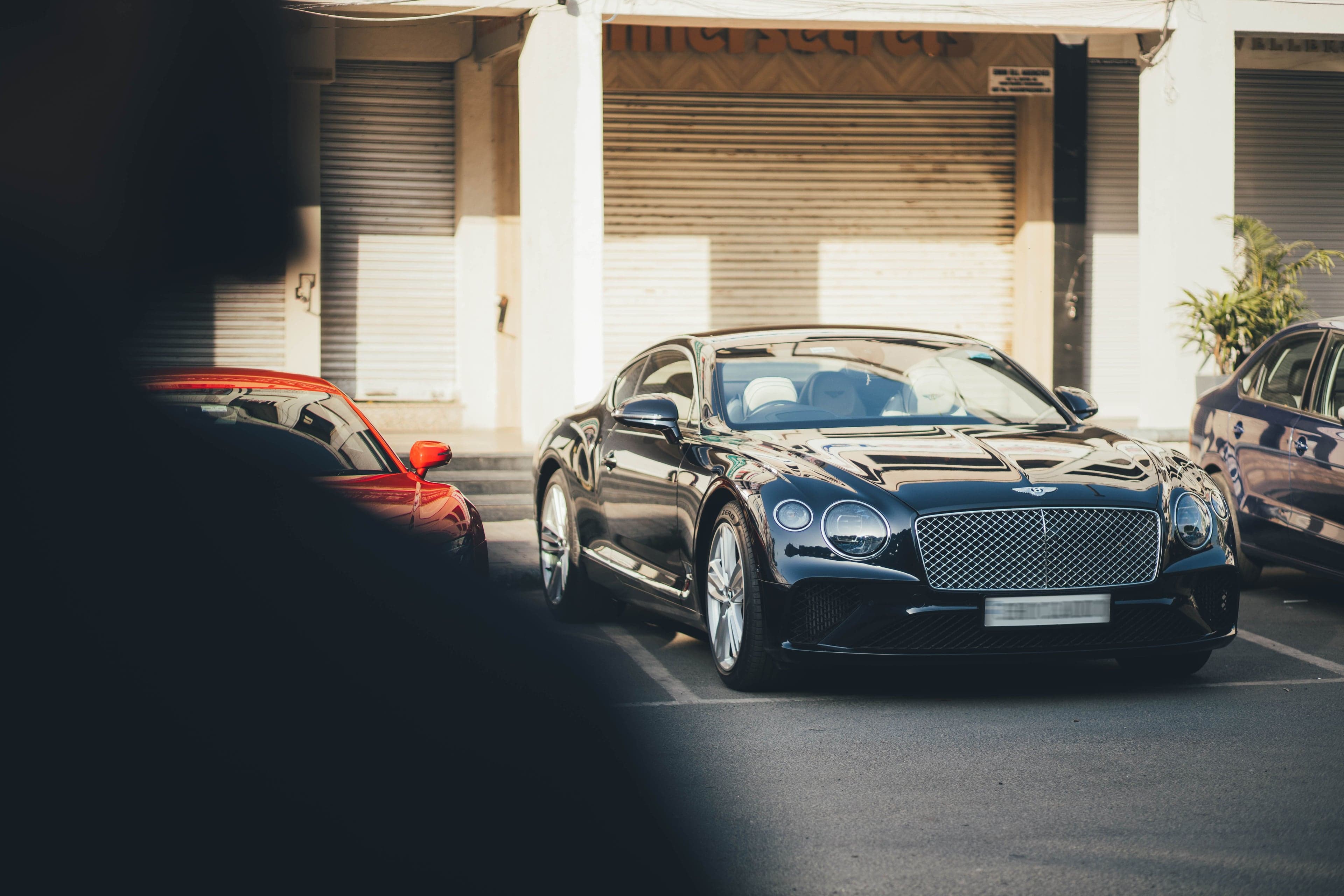 Luxe zwarte Bentley geparkeerd op een parkeerplaats tussen andere auto's.