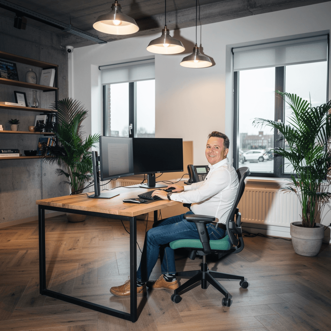 Man zit aan een bureau te werken met twee beeldschermen