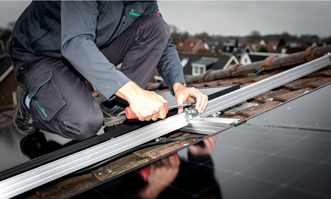Monteur monteert zonnepanelen op een dak
