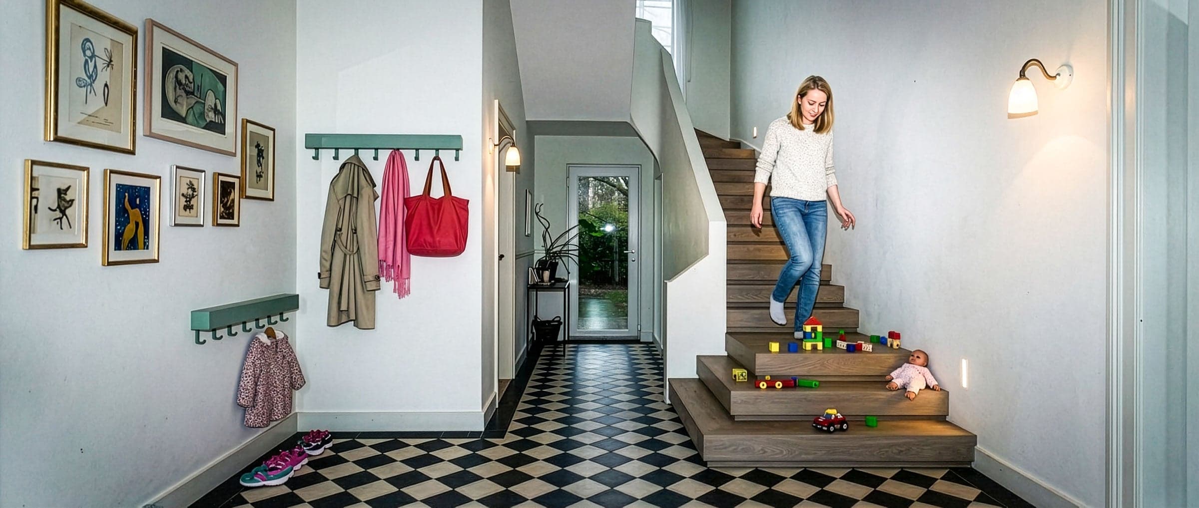 Bewoner loopt een trap af in een entreehal, terwijl speelgoed op de treden ligt en een struikelgevaar vormt